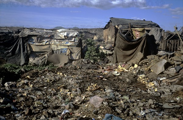 NICARAGUA, Managua Province, Managua, "The 'waste basket of Chureca' has existed since the late 1960's in the Acahualinca district of Managua, Nicaragua. It covers 42 hectares, is bombarded with thousands of tonnes of waste a day and is home to over 170 struggling families. By day over 1500 more Nicaraguans arrive at the site, some of whom are children who have been sent by their parents, others come by their own initiative. All compete with the adults to find, harvest and re-sell recyclable material. Of the minors who go to the waste basket - 88% it has respiratory problems, 62% suffer from parasites and 42% have serious skin diseases. Although the sky is clear and blue the air is thick of burning waste or rotting waste. Little houses or 'casitas' lie in a mixed muddle of rubbish and waste. The houses at the back of shot are made up of an eclectic collection of doors, wooden planks, dustbin bags, hanging bits of ripped tarpaulin, corrugated iron strips and whatever waste material seem...