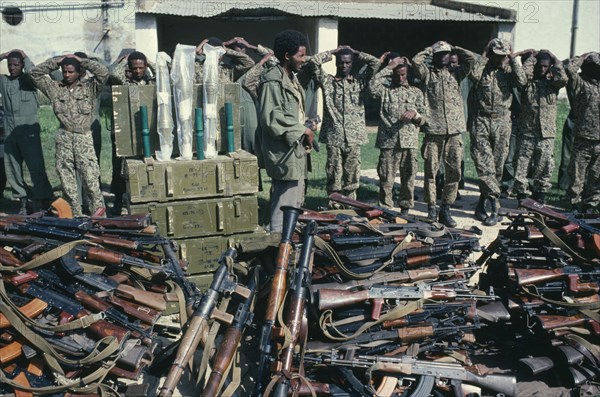 ERITREA, Military, Eritrean People’s Liberation Front soldier with prisoners and captured arms.