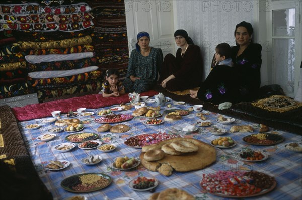TAJIKISTAN, Food, "Three women and two children sit by a large display of food laid out, awaiting the guests from the village wedding."