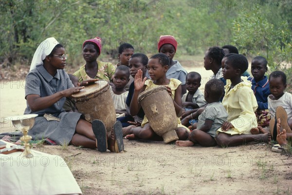 ZIMBABWE, Victoria District, Bondolfi Mission, Nun teaching children to play drums in mission school.