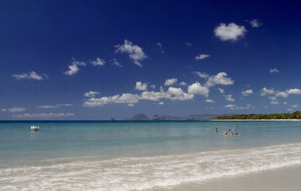 MARTINIQUE, Landscape, Beach, View from the waters edge across calm clear turquoise sea with people swimming in the water and hills seen in the distance