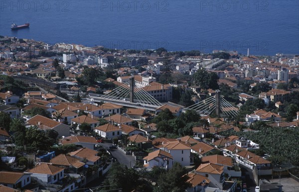 PORTUGAL, Madeira, Funchal, Elevated view over roof tops with the Motorway flyover leading to the airport amongst buildings running through the city