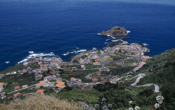 PORTUGAL, Madeira, Elevated view from the north coast road over Porto do Moniz rooftops and coastline