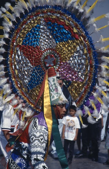 MEXICO, Mexico City, Our Lady of Guadaloupe Festival. Indian male dancer with large colorful headdress celebrating outside the Basilica of Guadaloupe