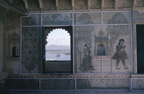 INDIA, Rajasthan, Udaipur, City Palace interior detail with painted walls and arched window framing view over Lake Pichola.