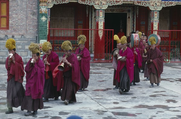 CHINA, Qinghai Province, Quezhang Lamasery, "Tibetan Yellow Hat Buddhists playing horns, drums and cymbals during ceremony."