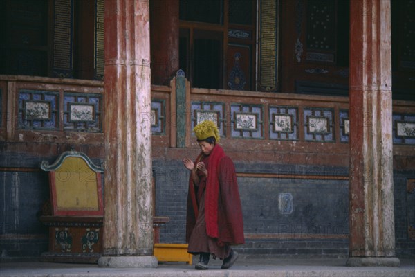 CHINA, Qinghai Province, Taer Lamasery, Tibetan Yellow Hat Buddhist monk calling other monks to prayer.
