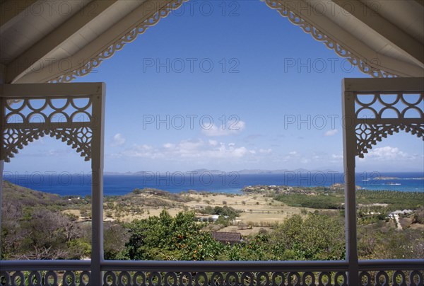 GRENADINES, Mustique, View from a carved Villa balcony over land and trees towards the coastline