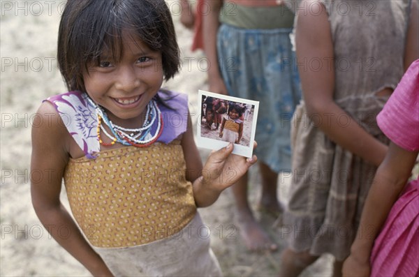 COLOMBIA, Amazonas, Santa Isabel, Macuna Indian girl holding a polaroid photograph of herself.
