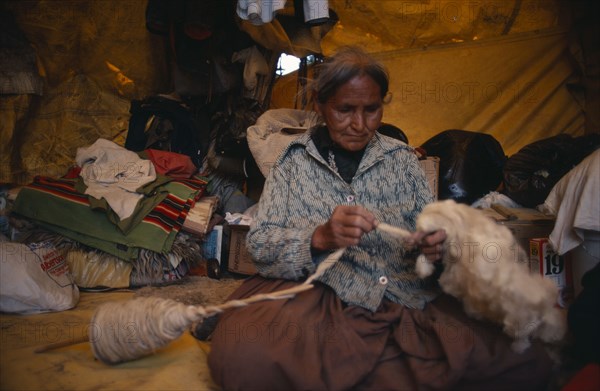 USA, New Mexico, Navajo Indian woman spinning wool in home.