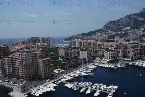 MONACO, Fontvielle, Elevated view over harbour with moored yachts on water towards tall buildings and houses built into hillside