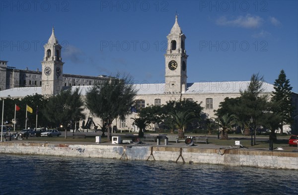 BERMUDA, Sandys Parish, Clocktower Mall formally the offices of the Royal Naval Dockyard seen from across water with trees along the banks
