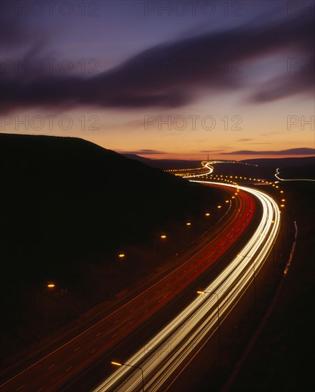 TRANSPORT, Traffic, Motorway, M62 Motorway. Elevated view over traffic in motion blur with light trails seen in late evening with a dramatic cloud formation