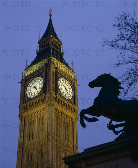 ENGLAND, London, Westminster. Big Ben Clock Tower and the statue of Boudicea in silhouette in the foreground seen in evening light