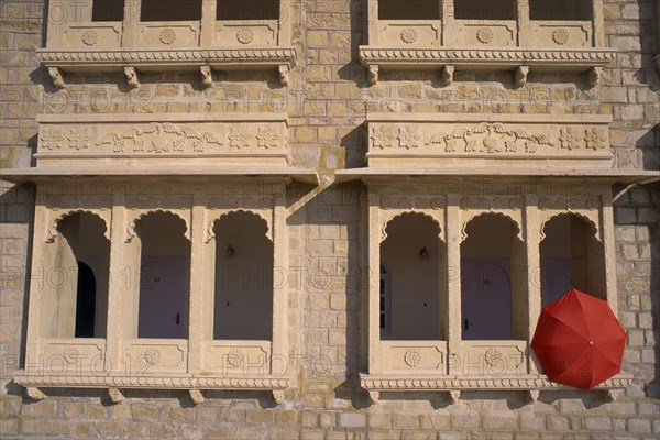 INDIA, Rajasthan, Jaisalmer, Hotel Himmatgarth Palace exterior with detail of windows and a red unbreller