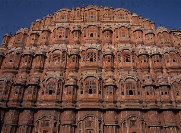 INDIA, Rajasthan, Jaipur, "Hawa Mahal. Exterior of pyramid shaped structure made of sandstone which has tier after tier of small casements each with tiny lattice worked pink windows, small balconies and arched roofs with hanging cornices"