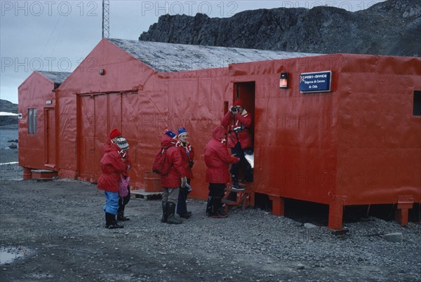 ANTARCTICA, King George Island, Teniente Marsh Station. Tourists wearing red jackets outside Post Office