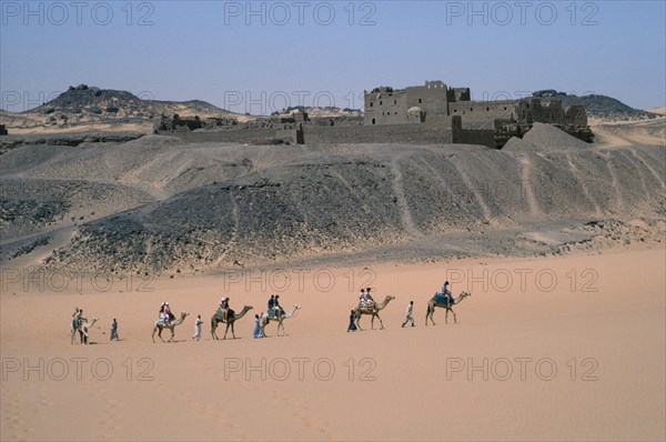 EGYPT, Nile Valley, Aswan, Monastery of St Simeon.  Deserted monastery on the west bank of the River Nile built in the 7th centuary AD.  Passing tourist camel train in foreground.