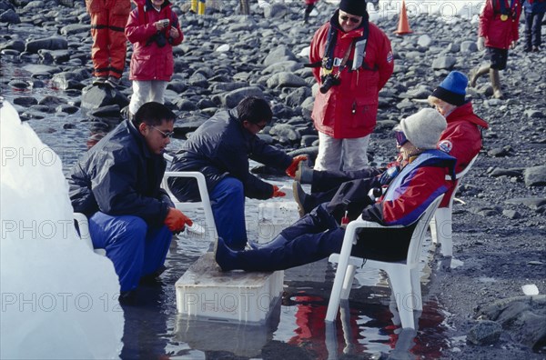 ANTARCTICA, Peninsula Region, Tourists sat on chairs having their boots cleaned before their departure