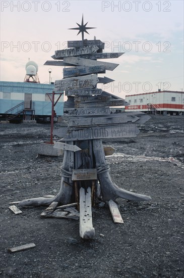 ANTARCTICA, King George Island, Russian Bellingshausen Station. Wooden sign post with star on top with arrows pointing to the distance home to Russia