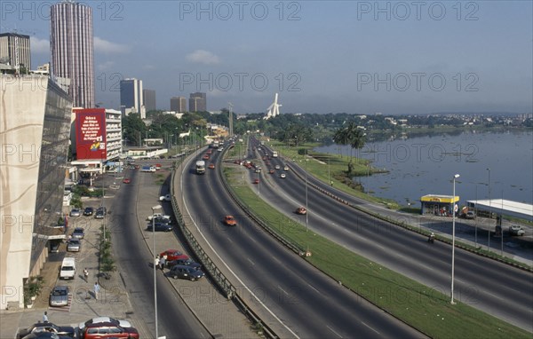 IVORY COAST, Abidjan, "Cityscape with multi lane traffic, skyscrapers and distant view towards modern exterior of St Paul’s Cathedral."