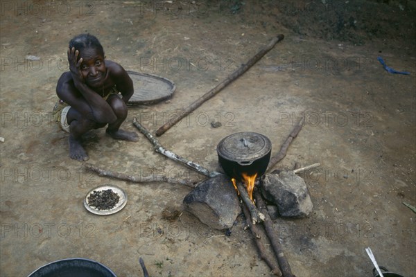 LIBERIA, People, Woman cooking on open fire with cooking pot balanced on stones.