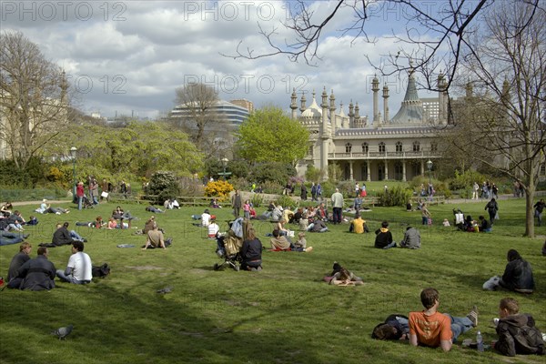 ENGLAND, East Sussex, Brighton, The Royal Pavilion gardens with people relaxing in the spring sunshine.
