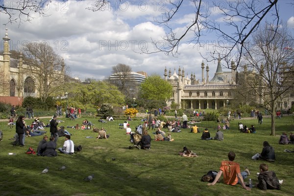 ENGLAND, East Sussex, Brighton, The Royal Pavilion gardens with people relaxing in the spring sunshine.