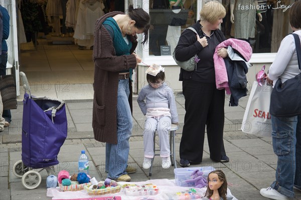 ENGLAND, East Sussex, Brighton, Young girl having her hair braiding in East Street