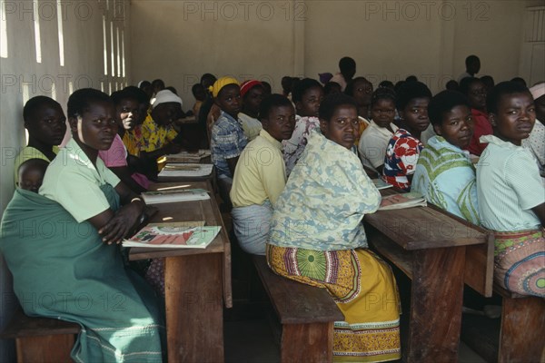 MALAWI, Kunyinda Camp, Mozambican refugee women attending adult literacy class. Young woman in foreground with child asleep on her back.