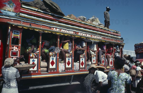 HAITI, Transport, Brightly painted and crowded taptap bus with waiting crowds and food sellers.
