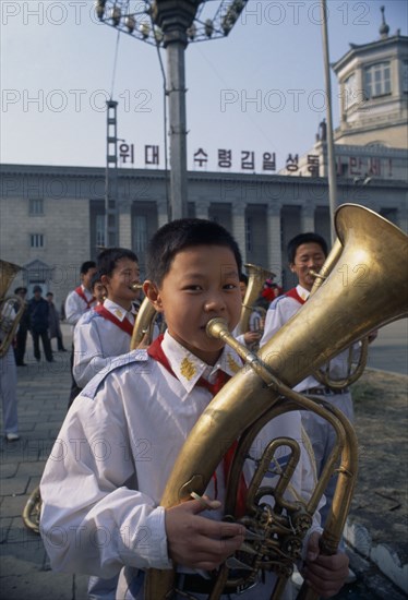 NORTH KOREA, North Hwanghhae Province, Pyongsan County, Boys in Juche band playing brass instruments outside railway station