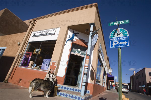 USA, New Mexico, Santa Fe, Native American man feeding his dog outside Father Sky Mother Earth Native American arts and crafts gallery on Water Street