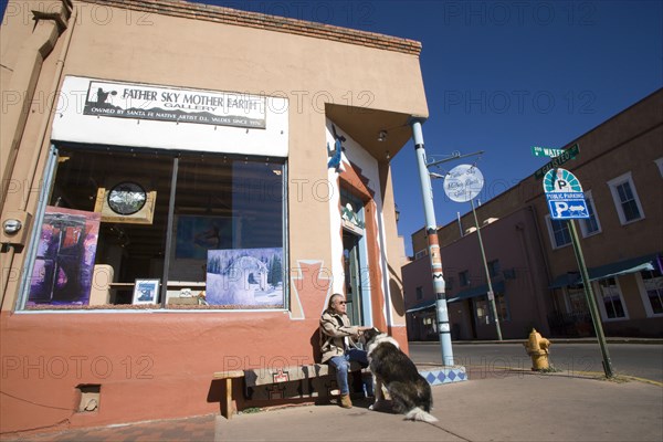 USA, New Mexico, Santa Fe, Native American man feeding his dog outside Father Sky Mother Earth Native American arts and crafts gallery on Water Street