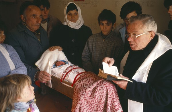 ALBANIA, Shkodra, Catholic Baptism with priest performing ceremony surrounded by family