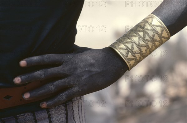 SUDAN, Tribal People, Cropped shot of Dinka man wearing brass bracelet decorated with abstract design.