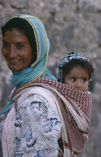 TURKEY, Diyarbakir, Portrait of Kurdish mother carrying child in sling on her back.