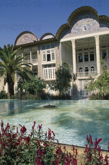 IRAN, Fars Province, Shiraz, Ghajar Palace Kakh -E -Eram Garden of Paradise. Palace exterior seen from across a pool with flowers in the foreground