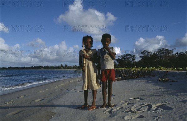 MADAGASCAR, Mananara, Two children standing on shoreline of sandy beach.