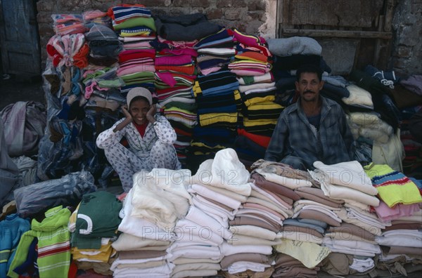EGYPT, Market, Smiling male and female vendors of pavement stall selling clothing.
