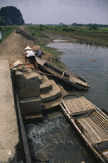 VIETNAM, Hoa Binh Province, Hoa Lu, People moving boat over dyke