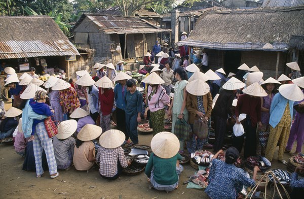 VIETNAM, Central, Hue, Village market near Mings Tomb with women wearing conical hats gathered around stalls selling fish and other food stuffs