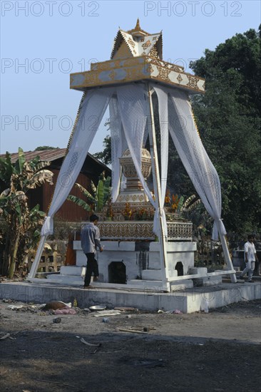 LAOS, Vientiane, Man about to light funeral pyre at a cremation