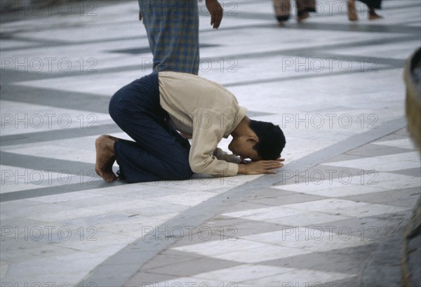 MYANMAR, Yangon, Man praying on floor at Shwedagon Pagoda