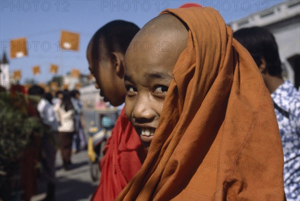 MYANMAR, Mandalay, Young Buddhist monk smiling wearing orange robes