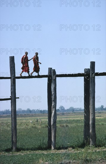 MYANMAR, Mandalay, Monks walking aross the wooden Amarapura Bridge over the flood plain