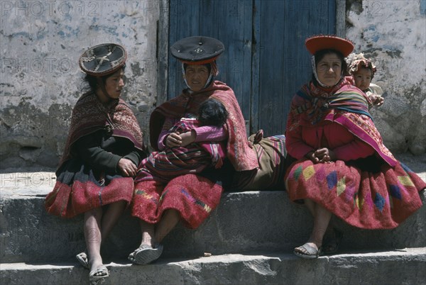 PERU, Cuzco, Ollantaytambo, Women carrying children in blanket slings resting in plaza after walk from village.
