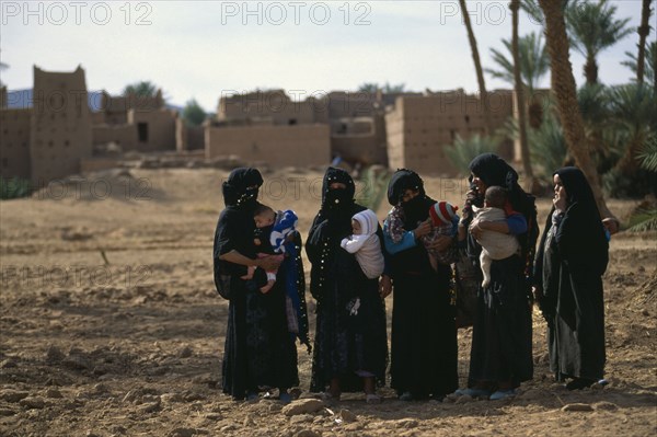 MOROCCO, Atlas Mountains, Women and babies from settlement in oasis near Zagora.