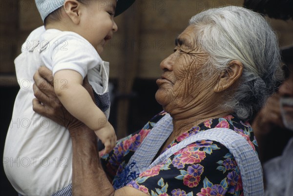 MEXICO, Oaxaca State, Tlacolula Village, Proud grandmother holding up grandson.