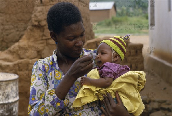 TANZANIA, People, Mother feeding baby daughter with a spoon.